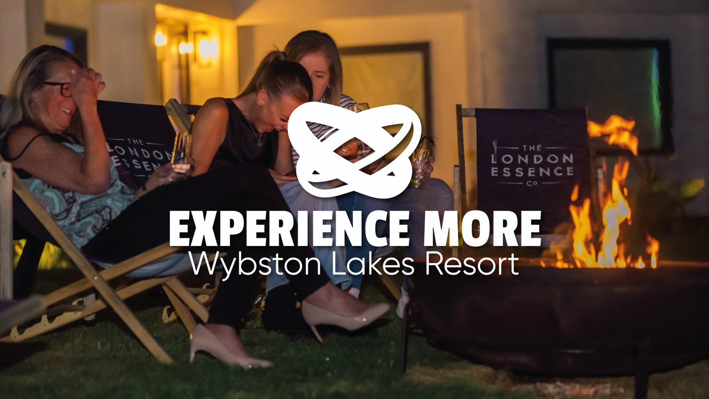 three women laughing around outdoor fire pit at night