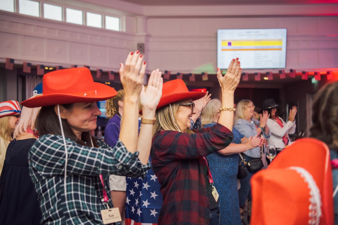 group of people clapping with red hats indoors