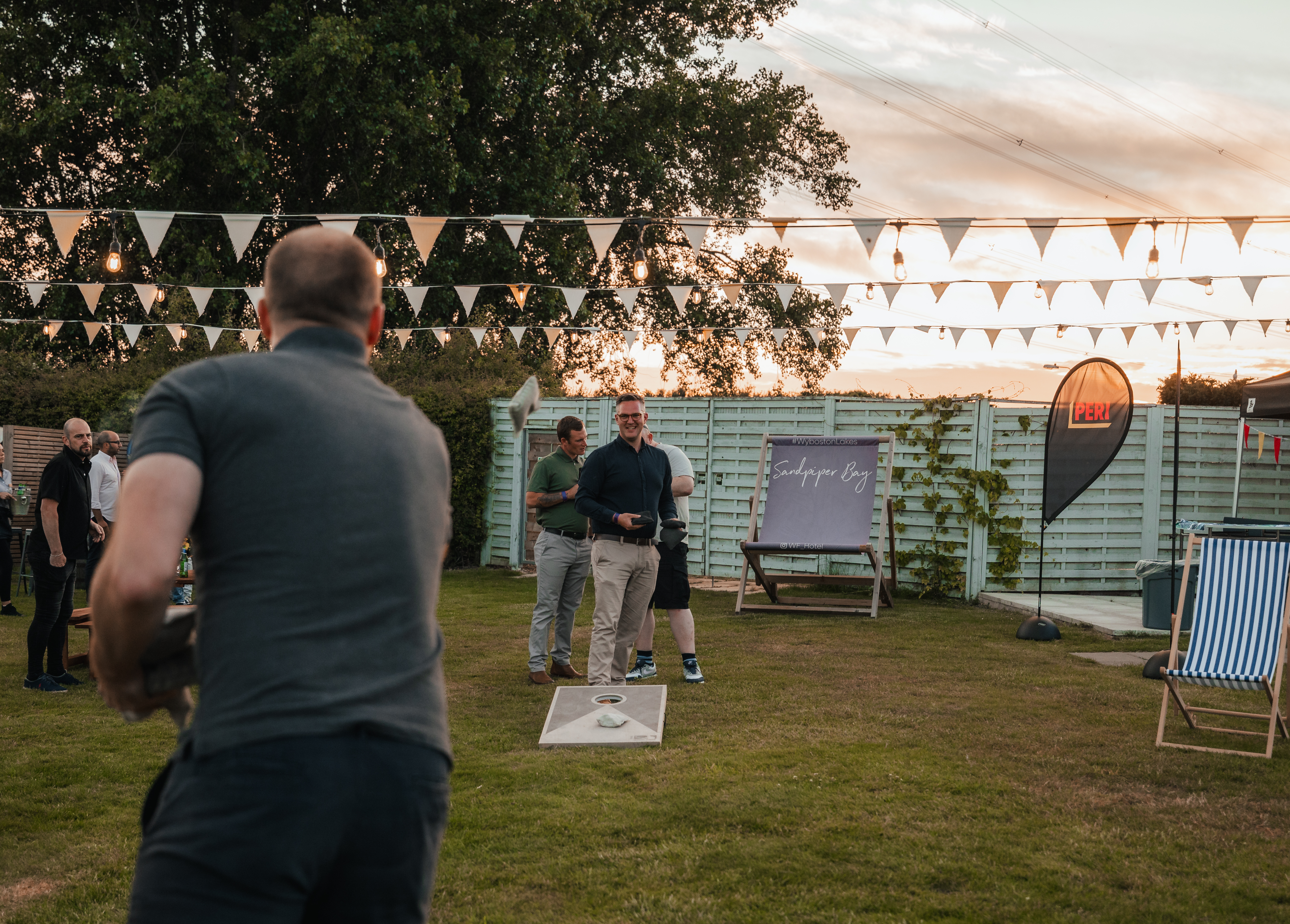 men playing outdoors under bunting lights at dusk