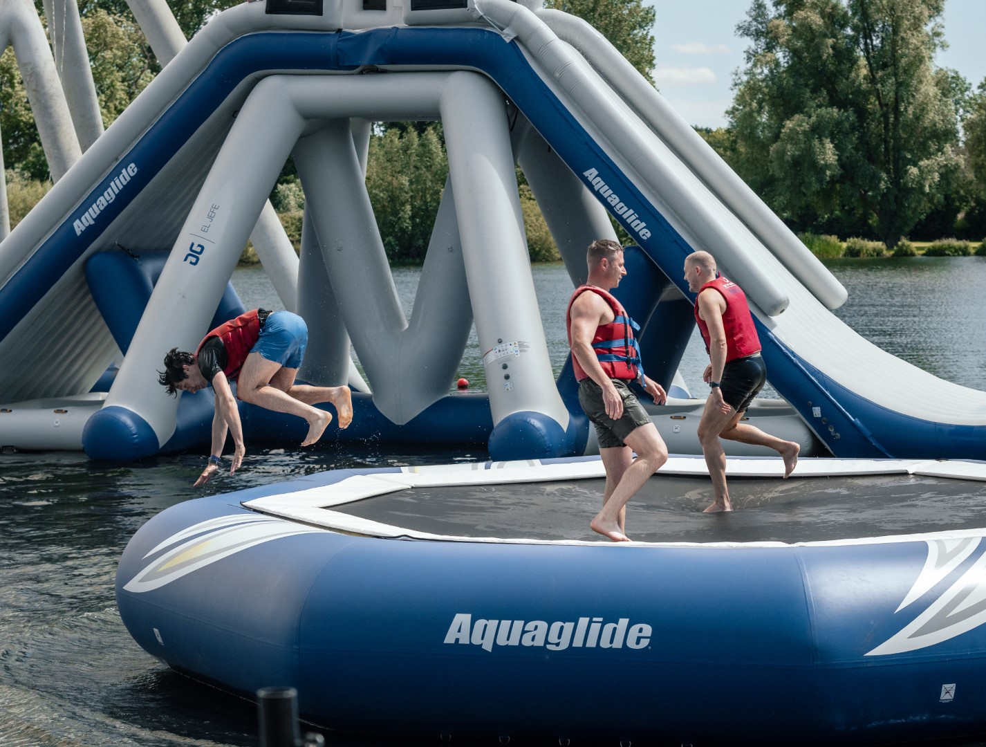 three people jumping and playing on inflatable water trampoline