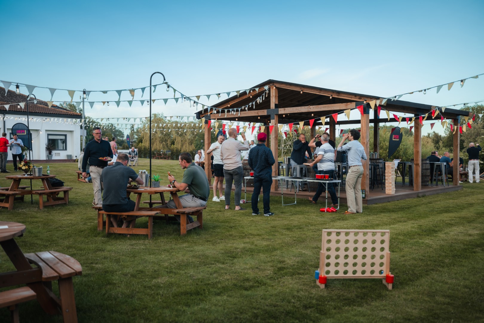 people socialising outdoors wooden pavilion summer evening