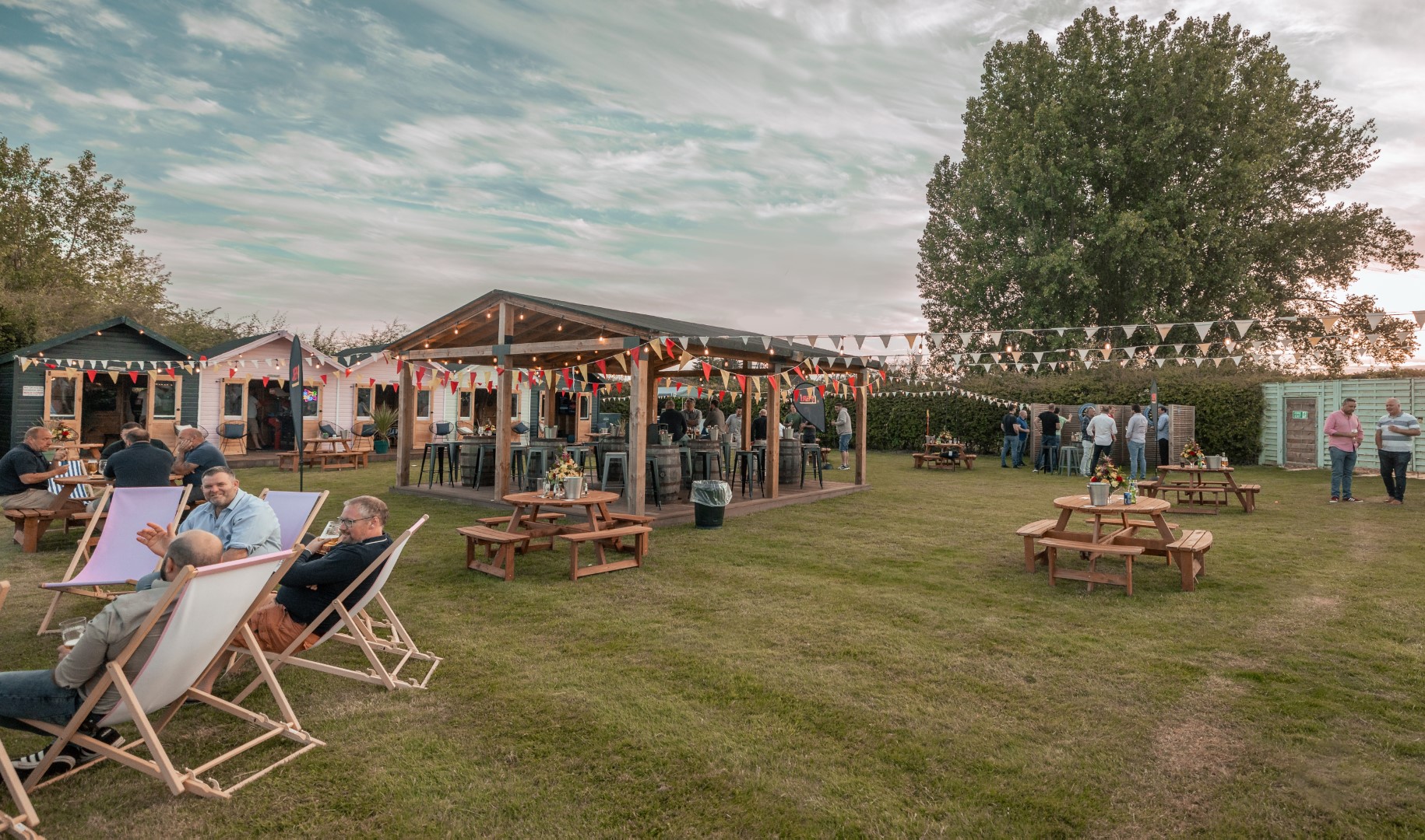 people relaxing outside in garden with deckchairs and tables