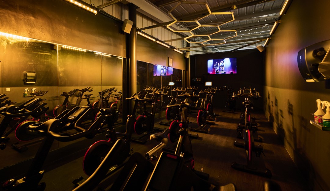 dimly lit spin class room with bikes and screen