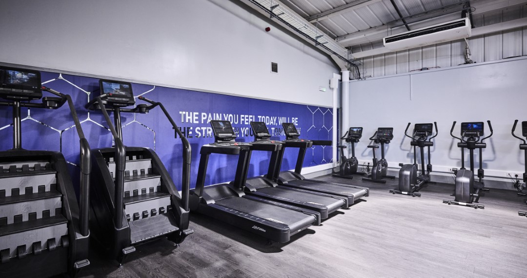 empty gym with treadmills exercise machines and motivational wall text