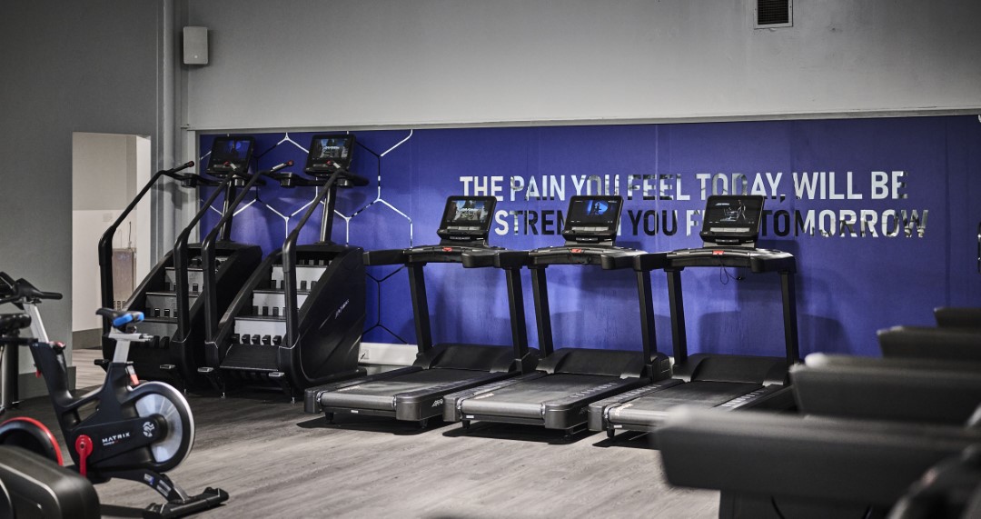 empty gym with exercise bikes stairs and treadmills