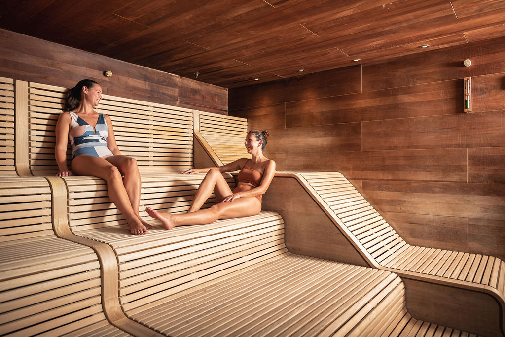 two women sitting chatting in wooden sauna room