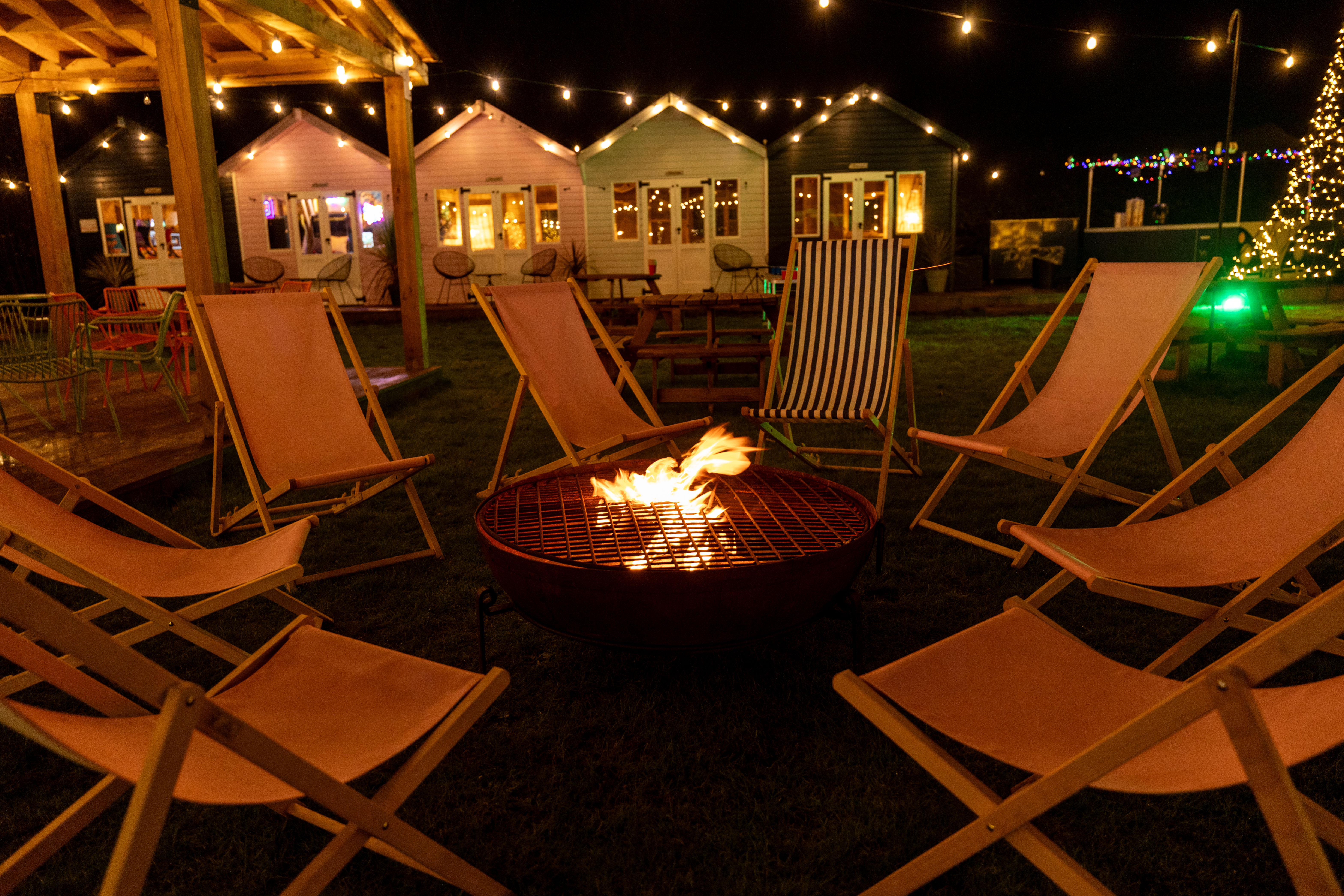 deck chairs around fire pit at night with cabins