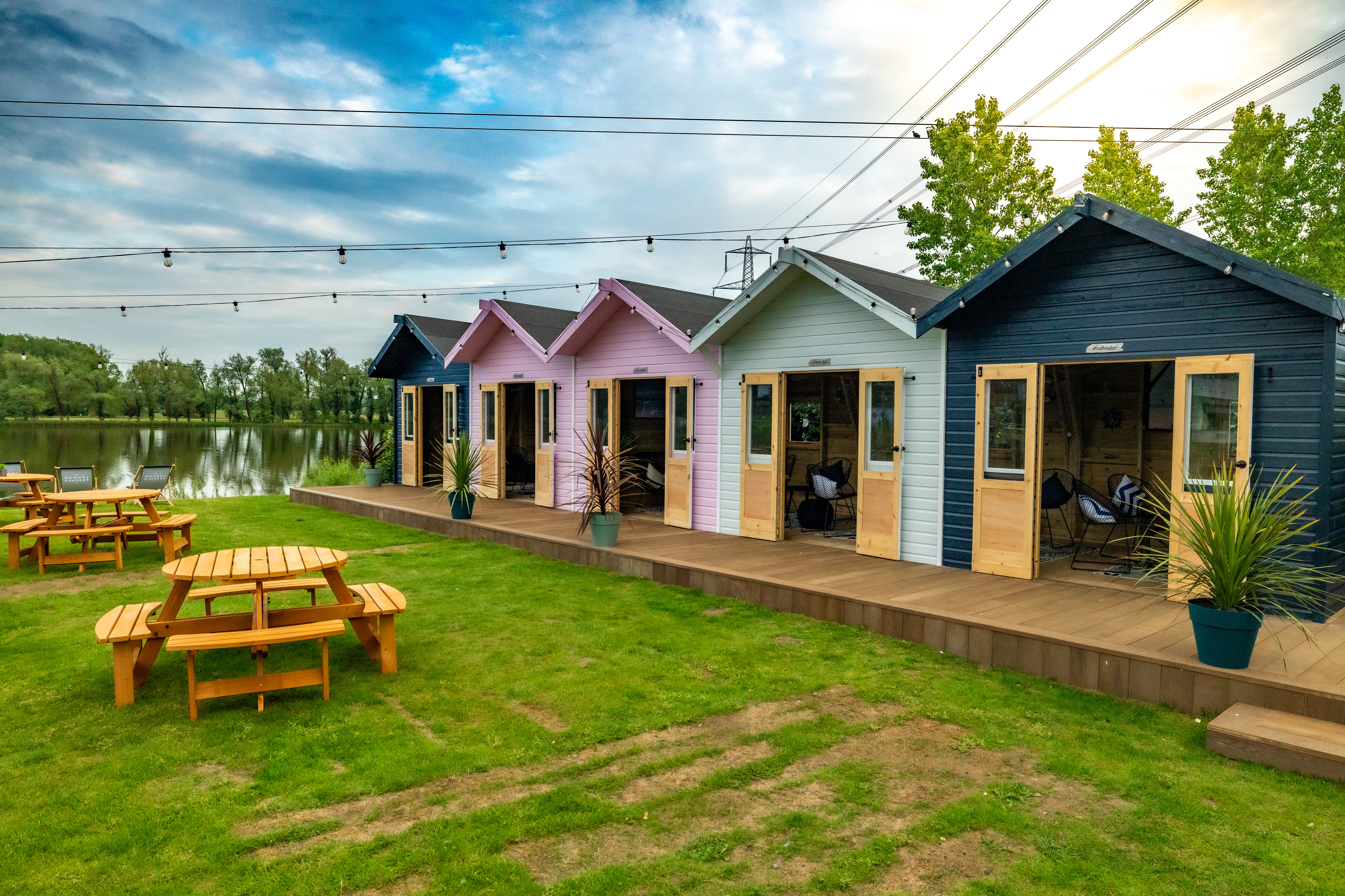 colourful wooden cabins with garden tables near lake