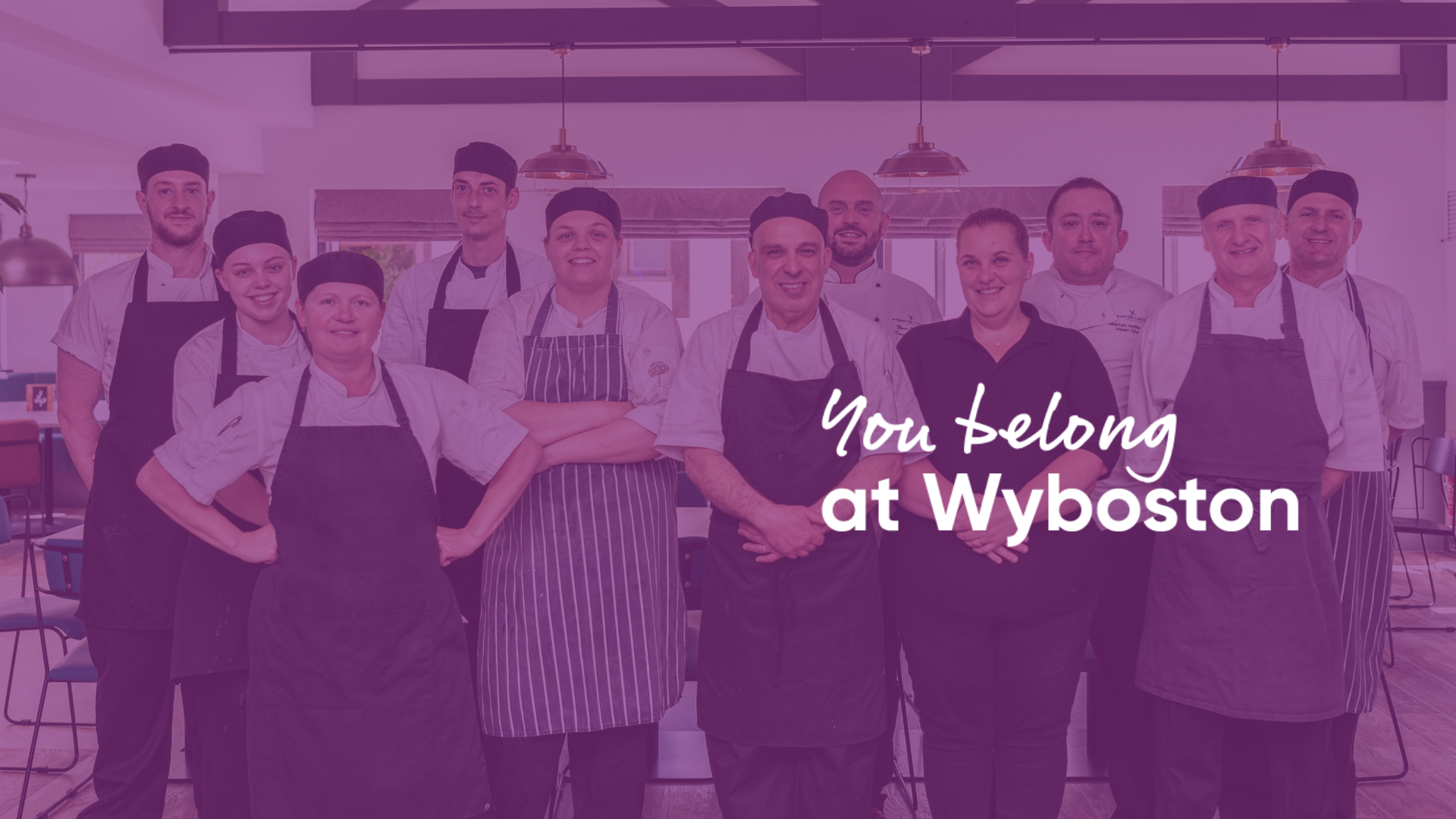 group of chefs and staff in kitchen uniform smiling
