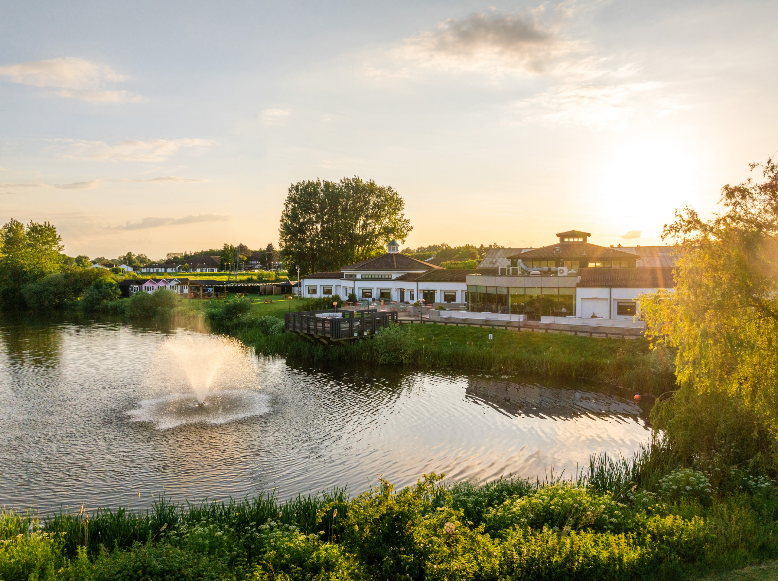 lake with fountain and building in background at sunset
