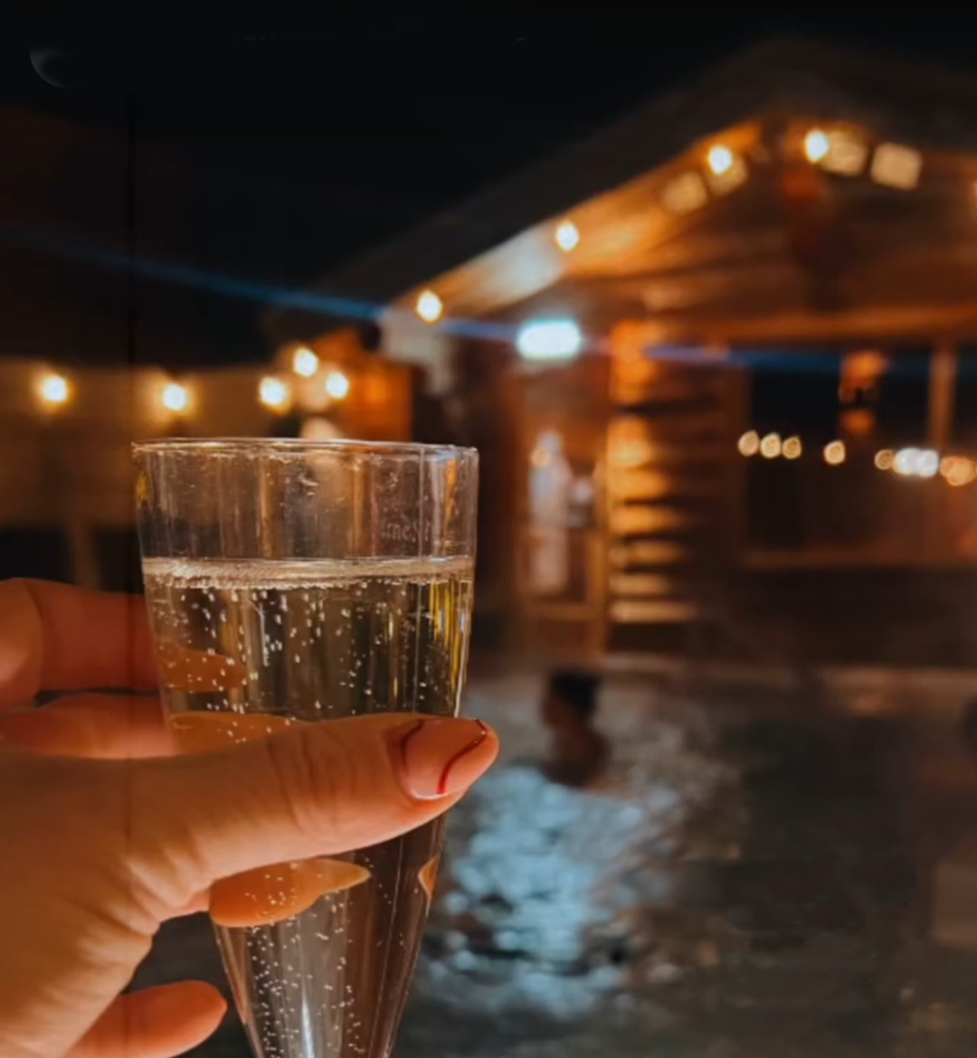 hand holding glass of bubbly drink by poolside at night