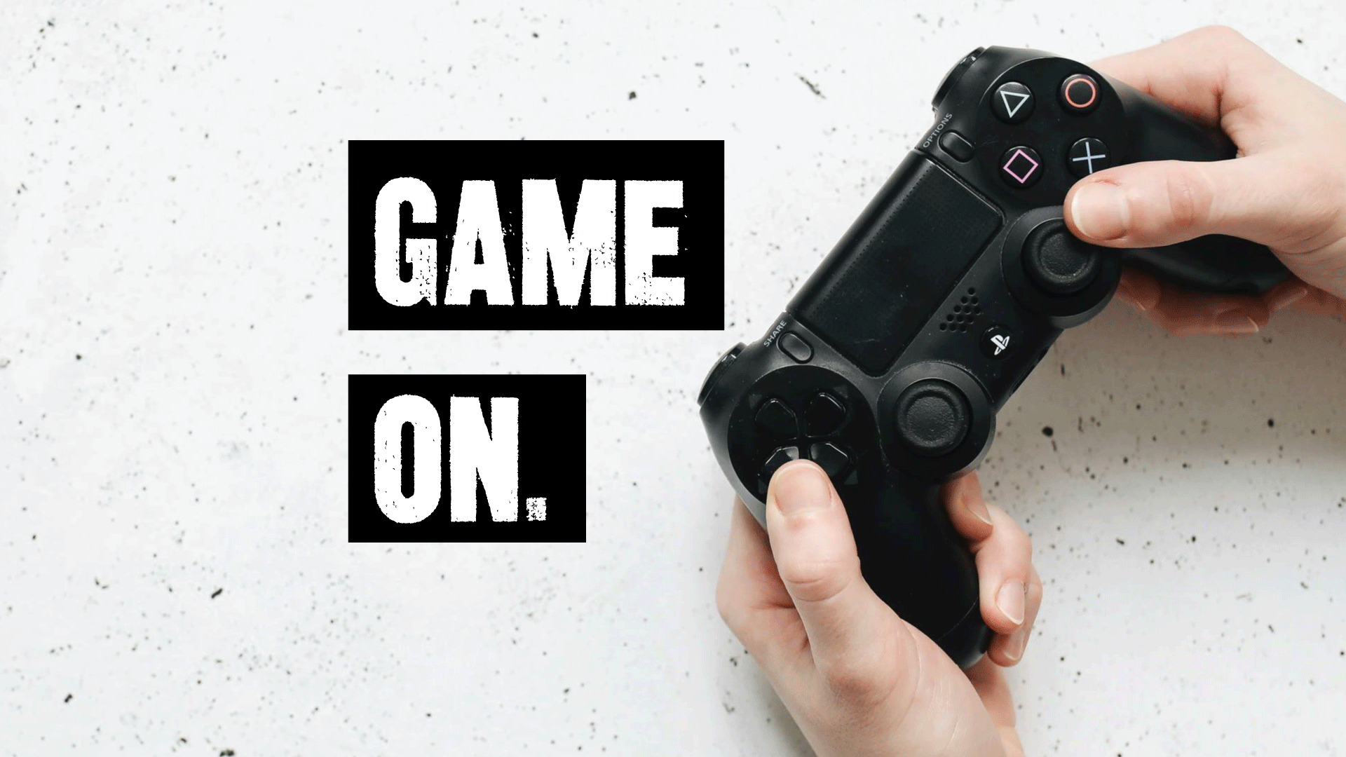 hands holding black game controller with game on text