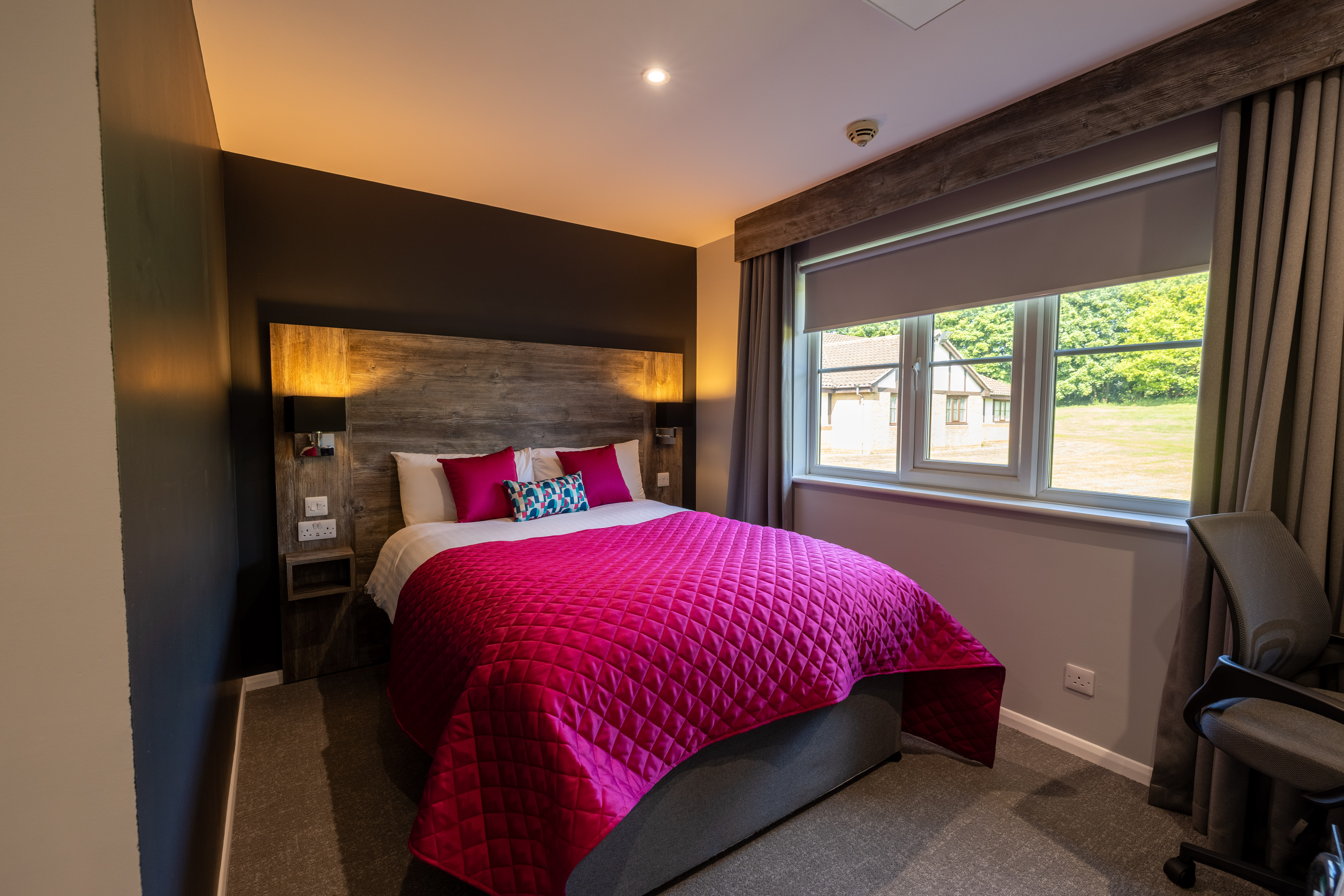 double bed with purple bedding and large window