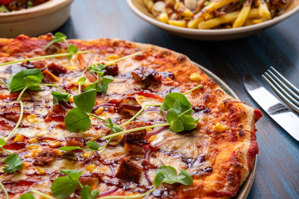 pizza with cheese barbecue sauce and microgreens on plate