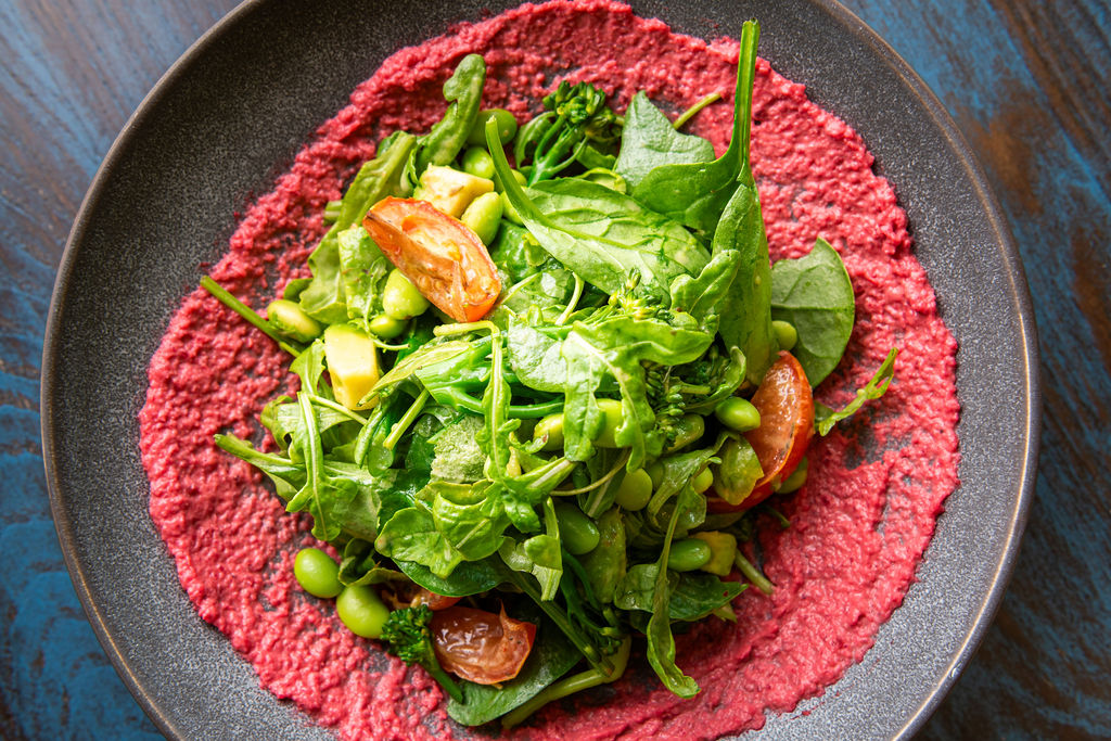 green salad with cherry tomatoes on pink hummus