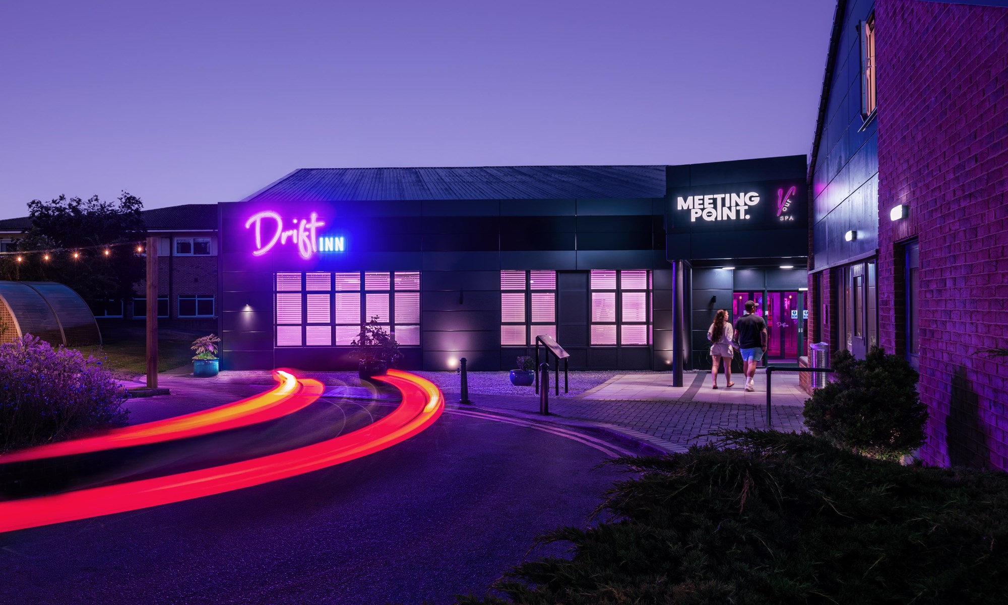 neon lit building with a couple walking towards entrance at