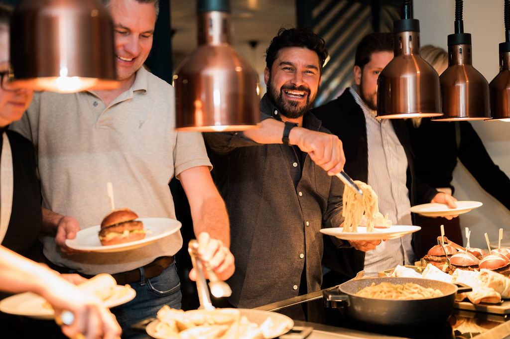 people serving themselves food at a buffet line