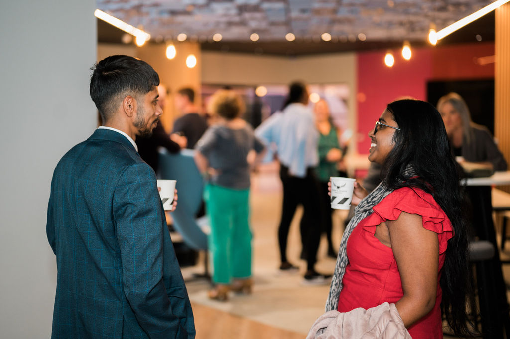 people talking at indoor social gathering holding cups