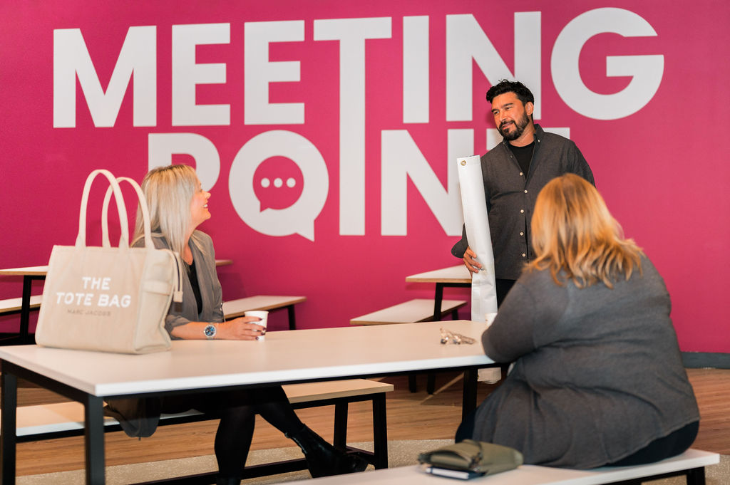 three people chatting in meeting room with pink wall