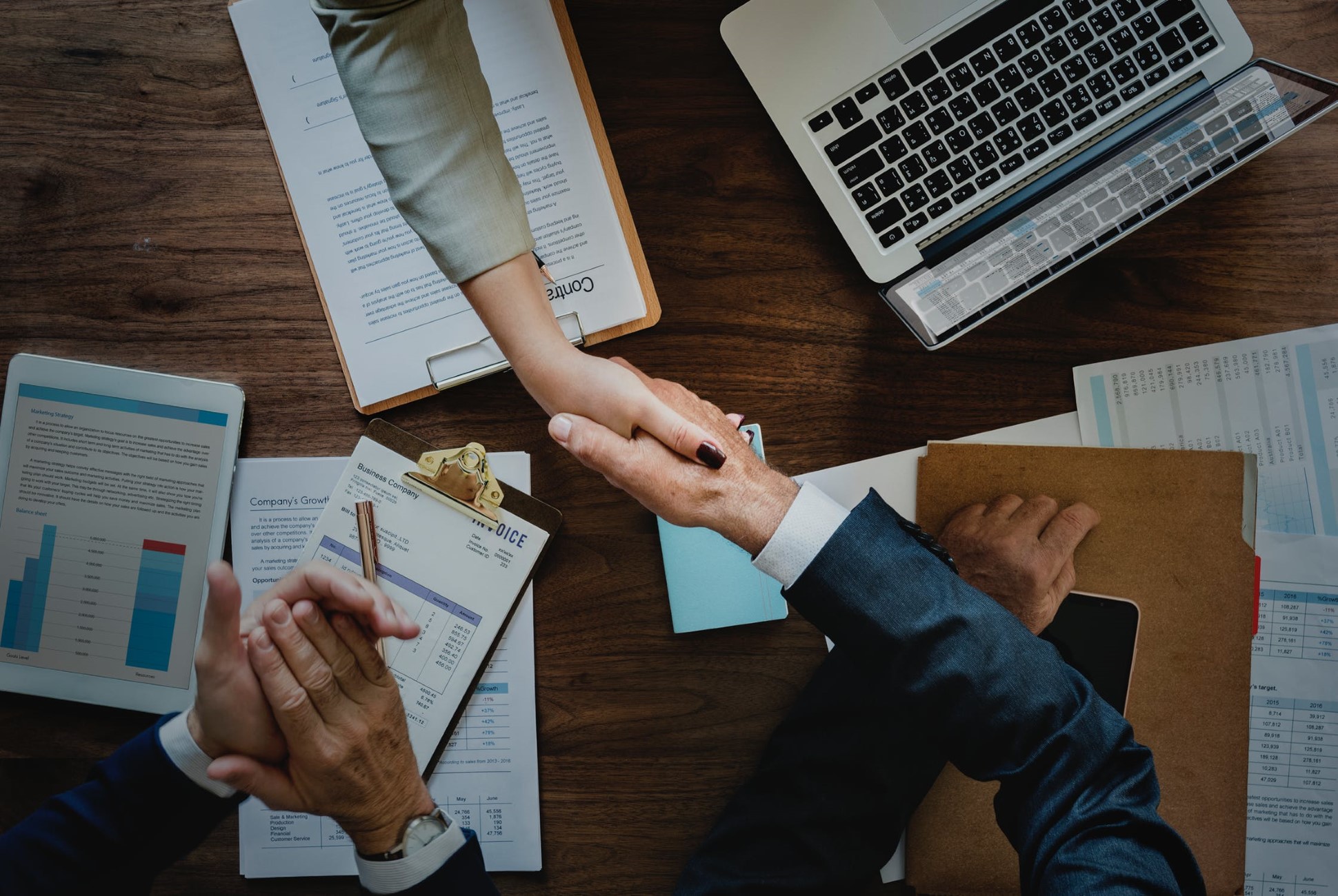 two people shaking hands over business documents