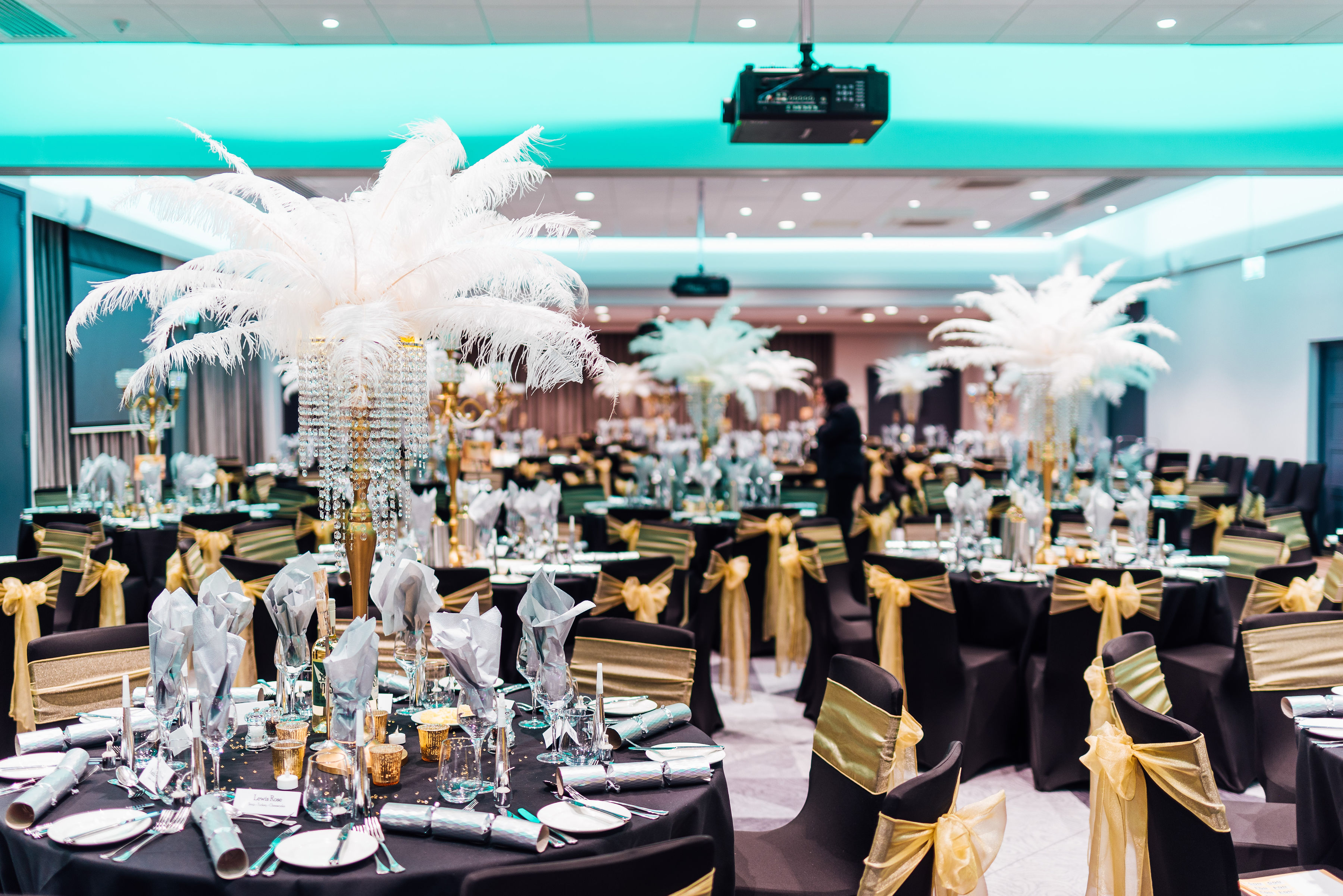 banquet hall with tables decorated with white feathers and gold